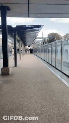 An Empty Train Station With A Glass Wall And A Canopy GIF
