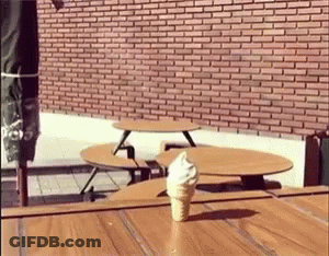 An Ice Cream Cone Is Sitting On A Wooden Table GIF