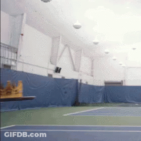 An Indoor Tennis Court With A Table In The Foreground And The Word Ny On The Wall GIF