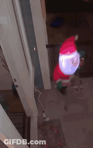 An Inflatable Santa Claus Is Hanging From A Doorway GIF