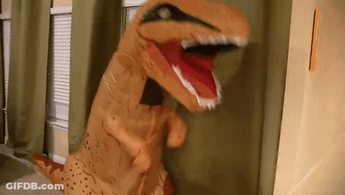 An Inflatable T-Rex Is Standing In Front Of A Window With Its Mouth Open GIF
