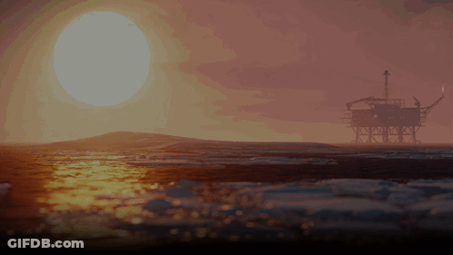 An Oil Rig In The Ocean At Sunset With The Sun Shining Through The Clouds GIF