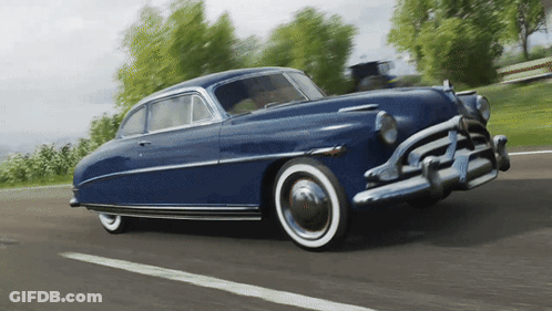An Old Blue Car With White Tires Is Driving Down The Road GIF