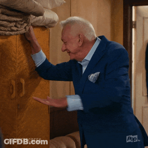 An Older Man In A Blue Suit Is Reaching Into A Closet With The Hashtag Schittscreek On The Bottom GIF