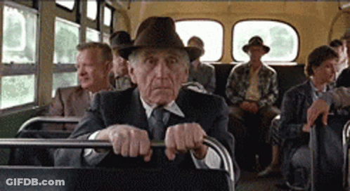 An Older Man In A Hat Is Sitting On A Bus With Other People GIF