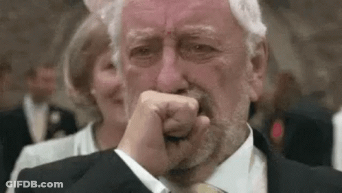 An Older Man In A Suit And Tie Is Crying While Covering His Mouth With His Hand . GIF