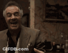 An Older Man In A Suit And Tie Is Laughing GIF