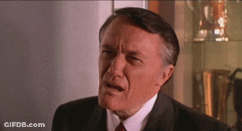 An Older Man In A Suit And Tie Is Making A Funny Face GIF