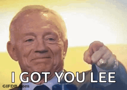 An Older Man In A Suit And Tie Is Pointing At The Camera . GIF
