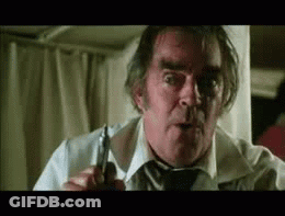 An Older Man In A White Shirt And Tie Is Holding A Pair Of Scissors . GIF