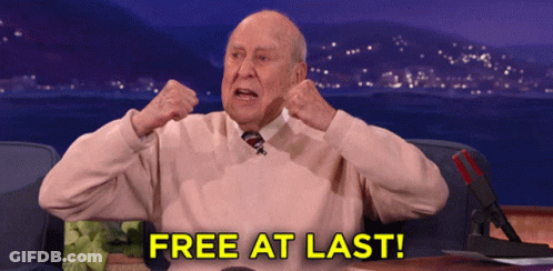 An Older Man Is Sitting At A Desk With The Words Free At Last Written On The Screen GIF