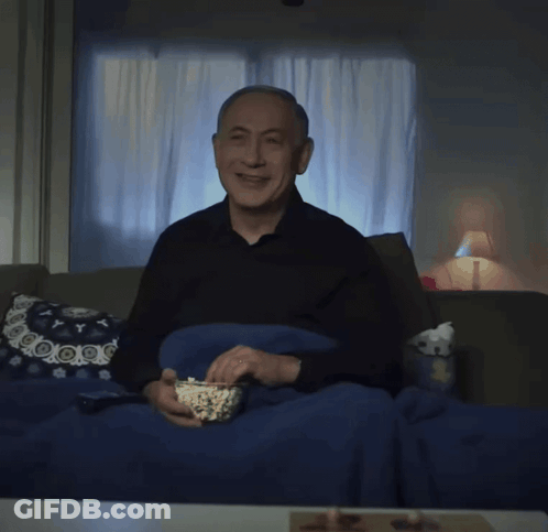 An Older Man Is Sitting On A Couch Eating Popcorn GIF