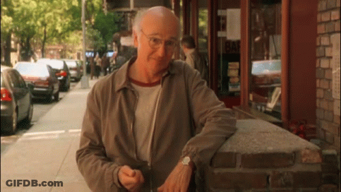 An Older Man Leans Against A Brick Wall In Front Of A Building That Says Bar GIF