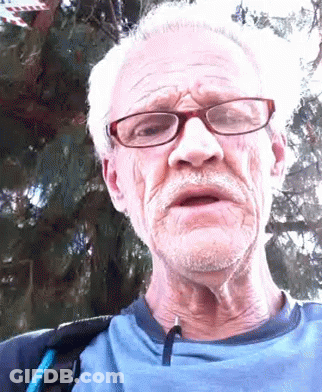 An Older Man Wearing Glasses And A Blue Shirt Is Making A Funny Face GIF