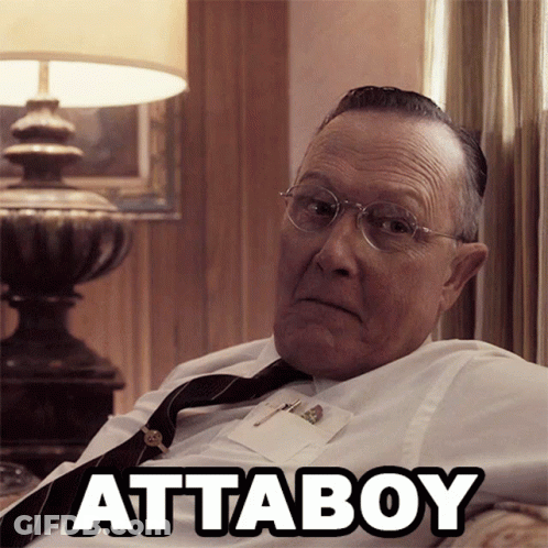 An Older Man Wearing Glasses And A Tie Is Sitting On A Couch With The Word Attaboy Written Above Him GIF