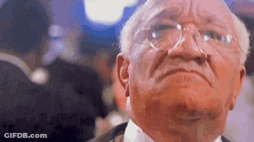 An Older Man Wearing Glasses And A Tuxedo Is Looking At The Camera . GIF