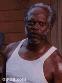 An Older Man With A Beard Is Wearing A White Tank Top And Making A Funny Face . GIF