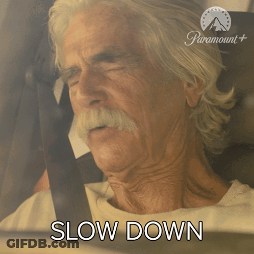 An Older Man With A Mustache Is Sitting In A Car With The Words Slow Down Behind Him GIF