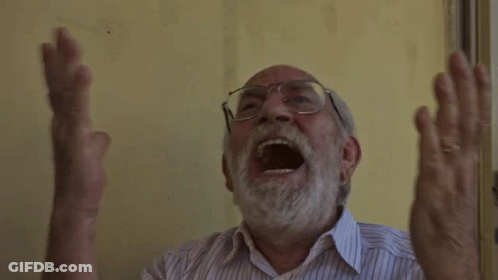 An Older Man With Glasses And A Beard Is Screaming With His Mouth Open GIF