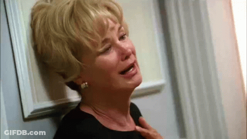 An Older Woman Is Crying While Leaning Against A Door . GIF