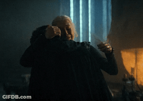 An Older Woman Is Hugging A Younger Woman In A Dark Room GIF