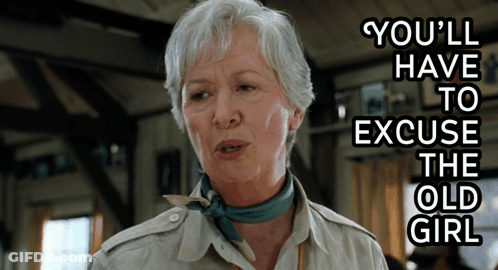 An Older Woman Says You 'Ll Have To Excuse The Old Girl While Wearing A Scarf Around Her Neck GIF