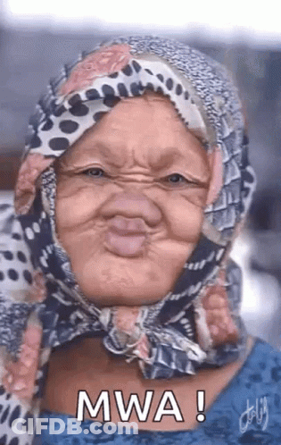 An Older Woman Wearing A Scarf Around Her Head Is Making A Funny Face . GIF