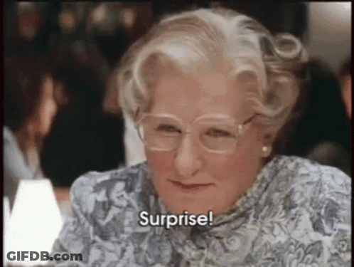 An Older Woman Wearing Glasses And A Floral Shirt Says Surprise . GIF
