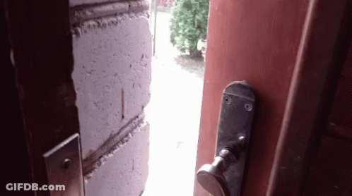 An Open Door With A Brick Wall Behind It And A Door Handle GIF