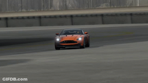 An Orange Aston Martin Sports Car Is Driving On A Track GIF
