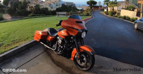 An Orange Harley Davidson Motorcycle Is Parked On The Curb GIF