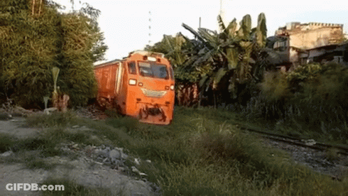 An Orange Train Is Going Down The Tracks In A Field . GIF