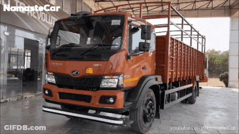 An Orange Truck Is Parked In Front Of A Namaste Car Revolution Store GIF