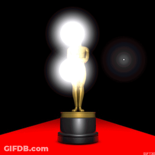 An Oscar Statue Is On A Red Carpet With A Light Behind It GIF