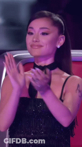 Ariana Grande Is Clapping Her Hands While Wearing A Black Dress . GIF