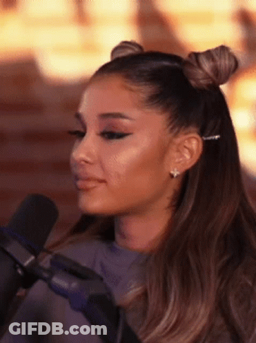 Ariana Grande Is Sitting In Front Of A Microphone With Her Hair In Two Buns . GIF