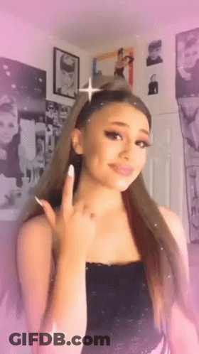 Ariana Grande Is Wearing A Black Tank Top And Making A Peace Sign . GIF