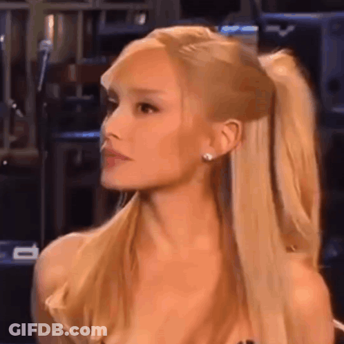 Ariana Grande Is Wearing A Ponytail And Earrings While Sitting In Front Of A Microphone . GIF