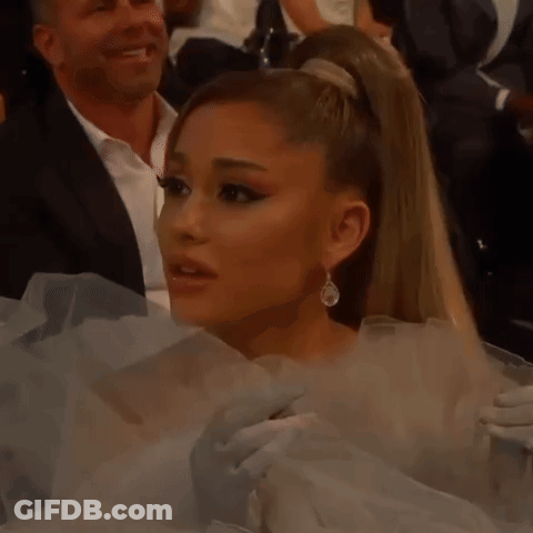 Ariana Grande Is Wearing A White Dress And Earrings While Sitting In A Crowd At Awards . GIF