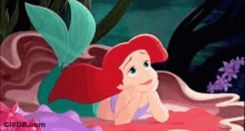 Ariel From The Little Mermaid Is Laying On A Rock GIF