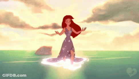 Ariel From The Little Mermaid Is Standing In The Ocean . GIF