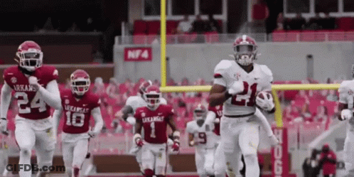 Arkansas Football Players Running On The Field With The Number 21 On Their Jersey GIF