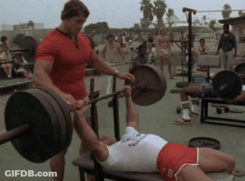 Arnold Schwarzenegger Helping Man Lift Barbell On Bench GIF