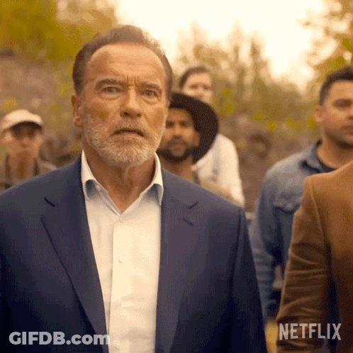 Arnold Schwarzenegger In Blue Suit Standing Before Crowd GIF