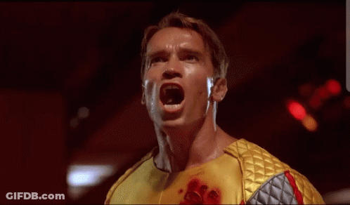 Arnold Schwarzenegger In Yellow And Silver Outfit With Blood GIF