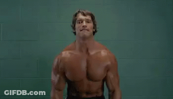 Arnold Schwarzenegger Lifting Dumbbells In Front Of Green Wall GIF
