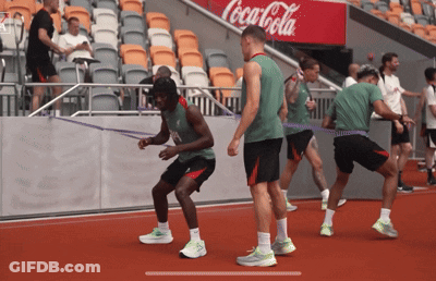 Athletes Doing Exercises In Front Of Coca-Cola Sign GIF