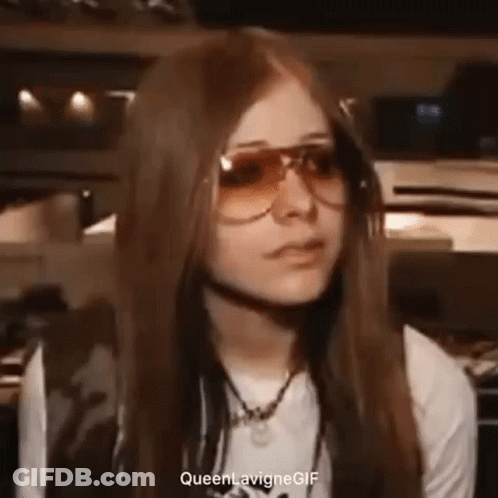 Avril Lavigne Is Wearing Sunglasses And A White Shirt While Making A Funny Face . GIF