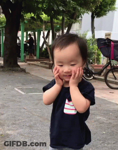 Baby Covering Face With Hands Next To Bicycle GIF