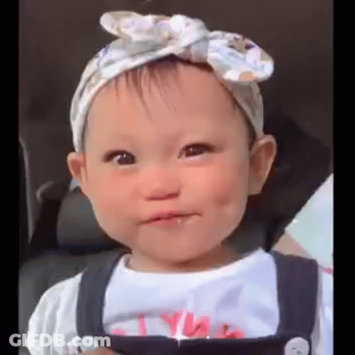 Baby Girl In Headband And Overalls Making Face GIF